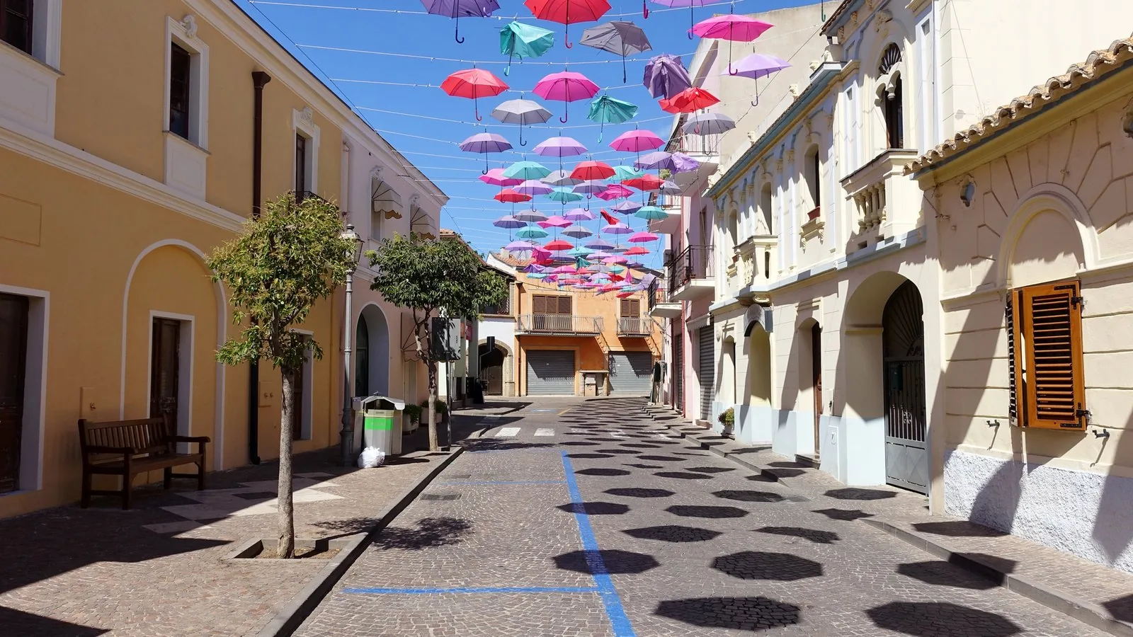 Una via del centro di Pula con gli ombrelli colorati sospesi sopra la strada