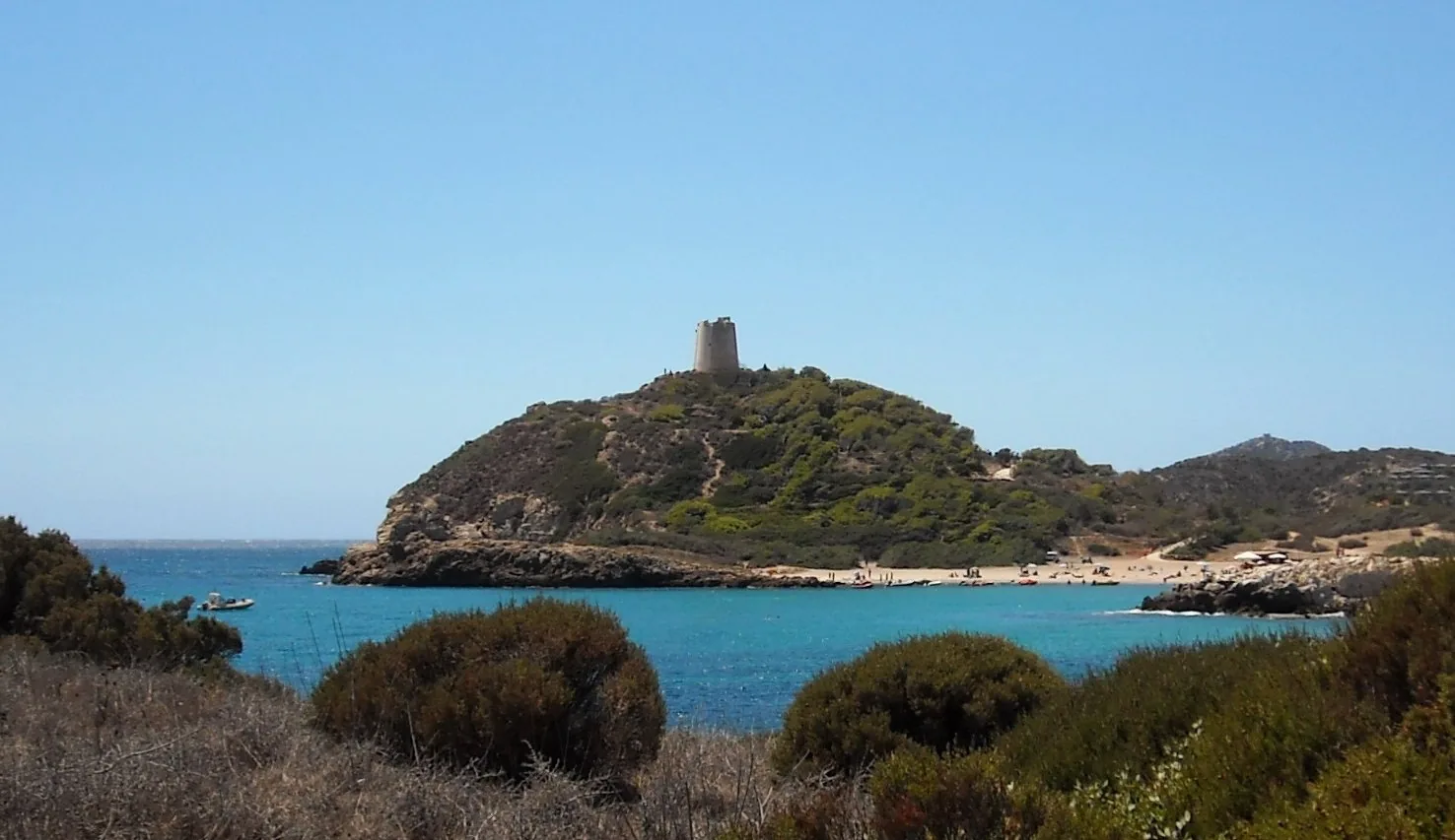 La torre di Chia sul promontorio, con il mare turchese sullo sfondo